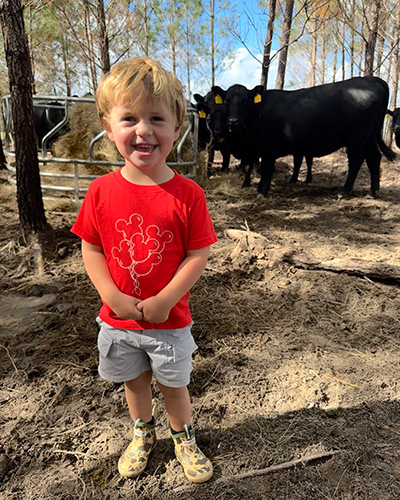 Smiling boy with cows in the background.